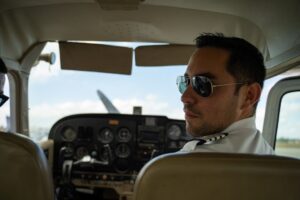 Pilot i uniform sitter ved instrumentpanelet i et småfly
