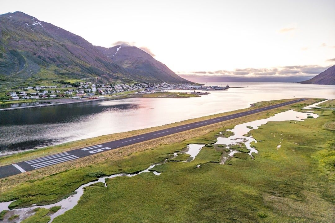 Kort rullebane langs fjord, omgitt av bratte fjell og våtmark